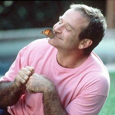 a man sitting in the grass with a butterfly on his nose