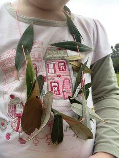 a young child wearing a t - shirt with leaves on it's chest and an object in the back