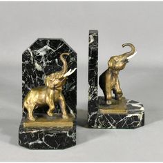 two statues of elephants and an elephant with tusks on marble bases, one in gold