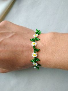 a woman's arm with a bracelet made out of beads and flowers on it