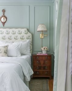 a white bed sitting next to a nightstand with a clock on it's side