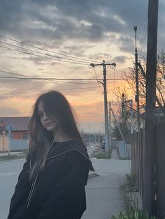 a woman is standing on the sidewalk with headphones in her ears and looking off into the distance