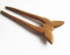 two wooden spoons are sitting on a white surface, one is shaped like a bird