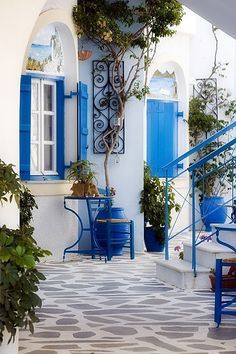 a blue and white house with potted plants on the front porch, stairs leading up to it