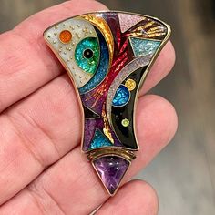 This stunning, vibrant pendant/brooch pin is circa 80s set in sterling silver with 14kt and 22kt accents and features a cabochon cut triangle amethyst gemstone made by Alexa & Peter Smarsh in Key Largo, Florida.    This pendant is signed by the artist and titled "Abstract Division".  This artist uses vibrant enamel colors with gold and silver foils and has breathtaking colors saturating the jewelry piece.  The triangle cabochon cut amethyst is bezel set and measures 11x8.87mm.  20.0 grams weight Collectible Enamel Cabochon Jewelry, Multicolor Cabochon Brooches For Collectors, Art Deco Multicolor Jewelry For Gift, Gold Multi-stone Enamel Jewelry, Multicolor Art Deco Jewelry For Gift, Unique Yellow Gold Enamel Brooch, Unique Multicolor Cabochon Brooches, Multicolor Art Deco Jewelry Gift, Artisan Collectible Jewelry Brooch