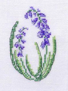 a cross stitch pattern with purple flowers in the center and green stems on each side