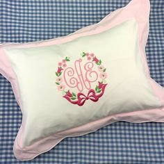 an embroidered monogrammed pillow on a blue and white checkered bed