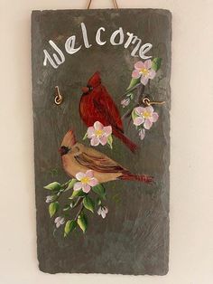 a welcome sign hanging on the wall with two birds sitting on it's branch