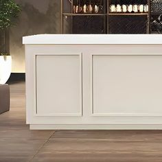 a large white counter sitting on top of a wooden floor next to a planter