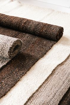 carpet samples laid out on top of each other in different colors and sizes, with one rolled up next to the rug