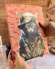 a hand holding up a drawing of a cat wearing a hat