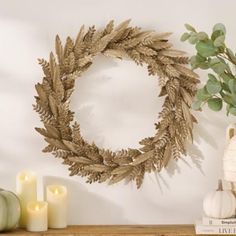 a wooden shelf topped with a wreath and candles