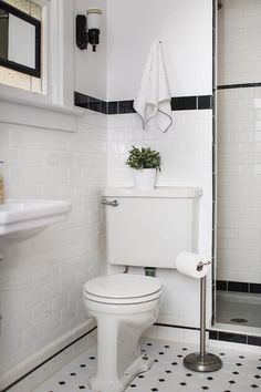 a white toilet sitting in a bathroom next to a walk in shower with black and white tile