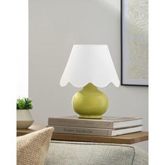 a green table lamp sitting on top of a stack of books next to a couch