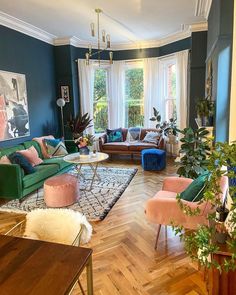 a living room filled with lots of furniture and plants on top of wooden flooring