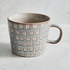 a blue and brown coffee cup sitting on top of a white table