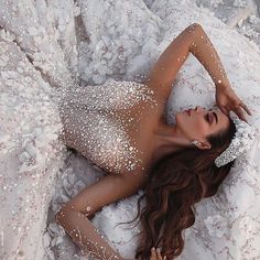 a woman laying on top of a bed wearing a white dress and headpieces