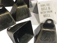 some metal items are sitting on a white surface and there is a sign that says ring the bell & wish them well