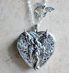 Fairy music box pendant. This heart shaped music box pendant is inspired by the gorgeous music box pendants of era's gone by. Music box is pill box size, please look at the dimensions for exact size.A perfect silver tone heart locket has been adorned with a layer of filigree and silver fairy with purple rhinestone on her wings. The filigree and fairy have been finished with resin to preserve the beauty of this pendant.The music box winds from a key on the back of the pendant. The pendant hangs f Fairy Music, Music Box Locket, Heart Shaped Locket, Silver Fairy, Round Locket, Purple Rhinestone, Funky Jewelry, Heart Locket, Pretty Jewellery