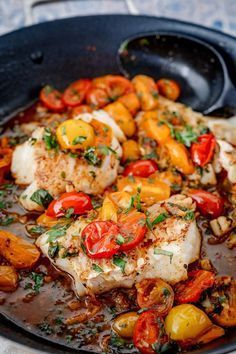 fish with tomatoes and potatoes in a skillet