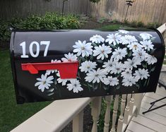 a black mailbox with white daisies painted on it