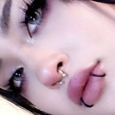 a close up of a woman with piercings on her nose and lip ring in front of her face