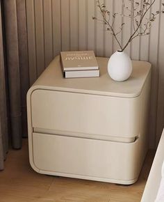 a white vase sitting on top of a nightstand next to a bed