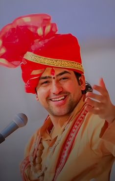 a man with a red turban on his head and microphone in front of him