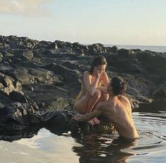 two people are sitting on rocks in the water