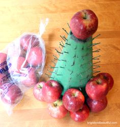 an apple cactus and some apples on a wooden table next to bags of candy canes