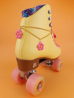 a yellow roller skate with pink wheels and flowers on it's laces against an orange background