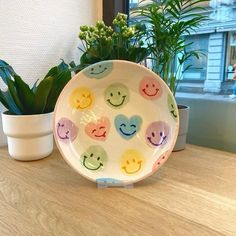 a plate with smiley faces on it next to a potted plant