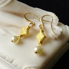 These dainty earrings consist of freshwater pearls suspended from flat diamond-shaped 24kt gold plated beads which are embossed on both sides with a quatrefoil pattern. They have 24kt gold plated ear wires. These earrings would be great for Roman re-enactments or for modern day wear. Limited edition design. 24kt gold plated ear wires. Length (from top of ear wire to bottom of earring) 4.2cm (1.65 inches) Please note: All photos are taken under natural light. However different computer screens, o Byzantine Earrings, Roman Costume, Quatrefoil Pattern, Ancient Jewelry, 24kt Gold, Dainty Earrings, Juno, Ear Wires, Handmade Earrings