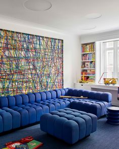 a living room filled with blue couches next to a large painting on the wall