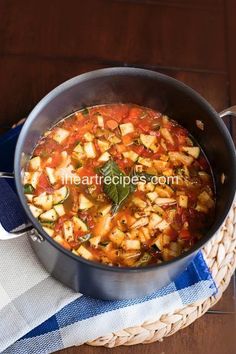 a pot filled with stew sitting on top of a table next to a blue and white towel