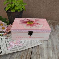 a pink box sitting on top of a wooden table next to a potted plant