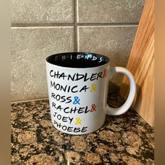 a white and black coffee mug with words on it sitting on top of a counter