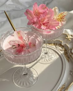 two dessert dishes with pink flowers in them on a white tray and gold trimmings