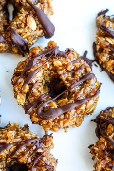 chocolate drizzled on the top of some granola cookies with nuts and chocolate