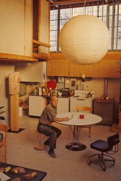 a man is sitting at a table in the middle of a room with lots of furniture