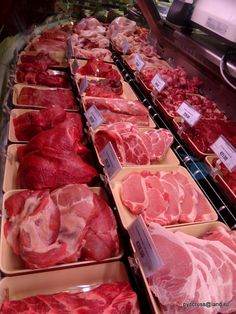 meat is displayed in trays on display at a grocery store, including ham and pork