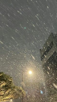 snow is falling in the air on a city street