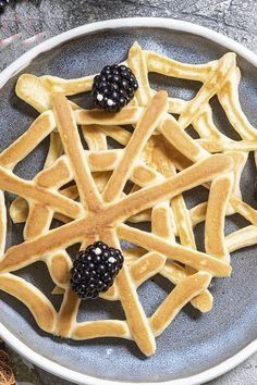 a plate with waffles and blackberries on it next to some cinnamon sticks