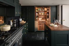 a kitchen with dark green cabinets and wooden counter tops