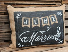 a pillow that says just married on the front and back of it, sitting on top of a wooden bench