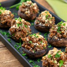 stuffed mushrooms with meat and parsley on a black tray, ready to be eaten