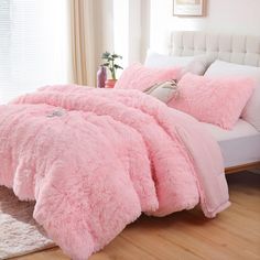 a bed covered in pink fluffy blankets and pillows