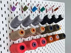 several spools of thread are hanging on a pegboard