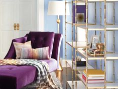 a purple couch sitting in front of a book shelf filled with books on top of a rug