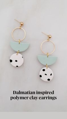 two circles with black and white dots hang from gold hoop earrings on a marble surface